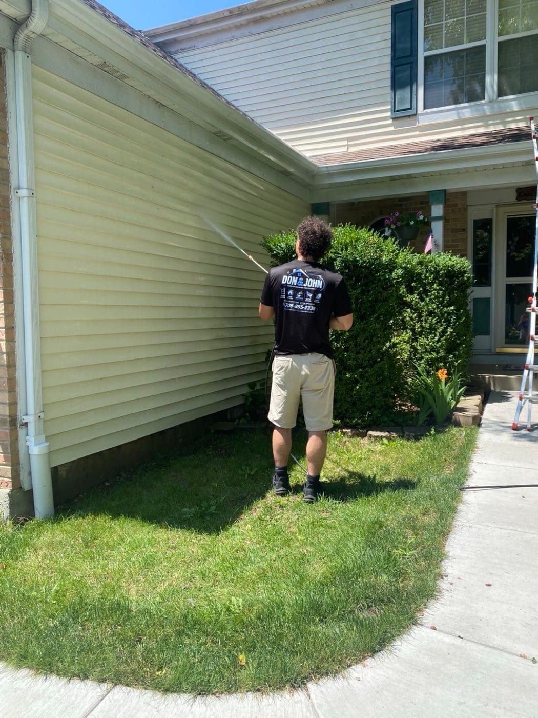 Crew member soft-washing a home's siding